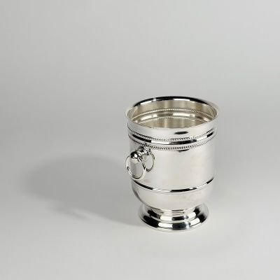 une tasse en argent munie d'une anse, posée sur une table