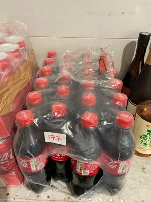 de nombreuses bouteilles de soda posées sur un comptoir à côté de bouteilles de bière
