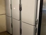 a row of refrigerators in a kitchen with a clock on the top