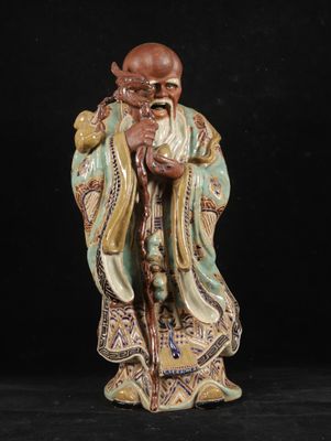 a chinese figurine of an old man holding a staff
