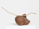 sculpture of a mouse on a white pedestal with a wooden stick sticking out of it ' s mouth