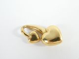 a gold plated heart charm on a white surface