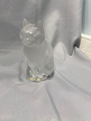 une figurine de chat posée sur une table près d'une fenêtre