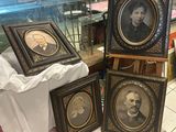 trois portraits encadrés d'hommes et de femmes sont posés sur une table devant une vitrine
