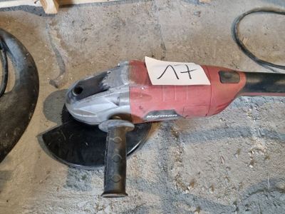 une perceuse électrique rouge et noire posée par terre