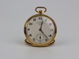 une montre de poche en or avec un cadran blanc sur une surface blanche