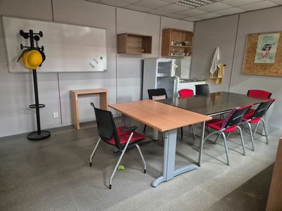 a room with a table, chairs, and a refrigerator in it