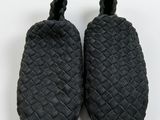 two pairs of black slippers on a white surface