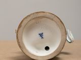 a close up of a white and blue vase on a table