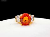 an orange sapphire and diamond ring on a white plate