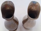 two silver vases sitting on a white surface
