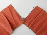 an image of a pair of orange leather pieces on a white surface