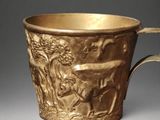 a gold cup with a design of animals and people on it