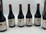 six bottles of wine are lined up in a row on a table