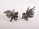 une paire de figurines de coqs en métal sur fond blanc