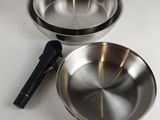 two stainless steel pans sitting on top of a white counter