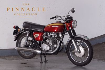 a red motorcycle parked in front of a white wall