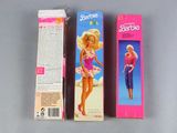 two boxes of barbie dolls are sitting next to each other on a table