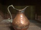 a copper pitcher sitting on a wooden table