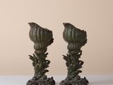 pair of green artichokes on a white table with a beige background