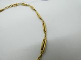 a close up of a gold necklace on a white surface
