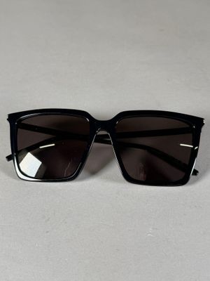 un gros plan sur une paire de lunettes de soleil noires posées sur une surface blanche