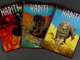 three books of hard - cover comics are sitting on a table