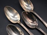 three silver spoons and two silver spoons on a black surface