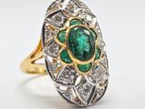 gros plan d'une bague avec une pierre verte entourée de diamants