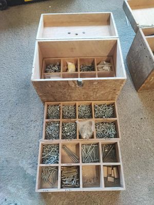 une boîte en bois remplie de vis et d'écrous, posée par terre
