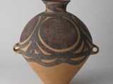un vase brun et noir posé sur une surface blanche