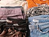 a pile of clothes and a purse sitting on a bed