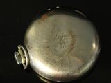 a silver pocket watch sitting on a black surface