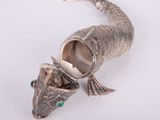 a silver fish shaped object on a white surface