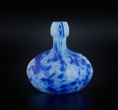 un vase en verre bleu et blanc posé sur une surface noire