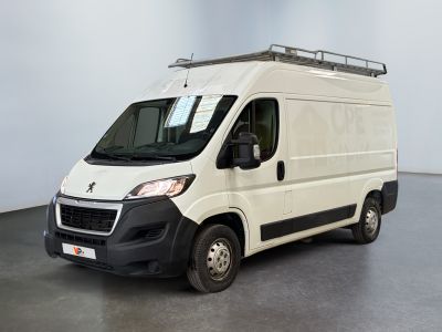 La camionnette blanche est garée dans une pièce au sol gris.