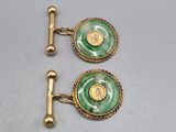 a pair of green and gold cufflinks on a white surface