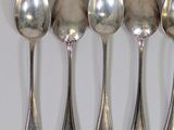 six spoons are lined up in a row on a white surface