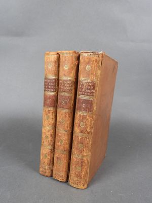 trois vieux livres empilés les uns sur les autres sur une surface grise
