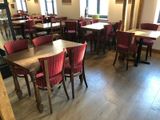 many tables and chairs in this restaurant with red upholstered chairs