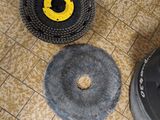 three cleaning brushes on the floor next to a trash can