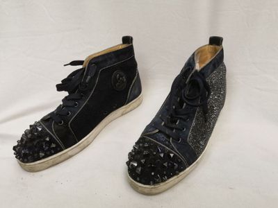 une paire de chaussures noires ornées de clous, posée sur une surface blanche