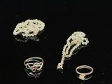 trois bagues, un collier et une bague posés sur un fond noir