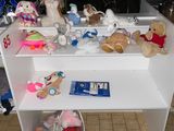 de nombreuses peluches posées sur une étagère blanche dans une pièce