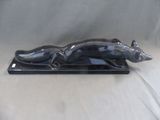 statue d'un chat noir sur un socle noir, sur fond blanc