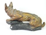 bronze statue of a dog on a rock on a white background