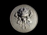 a close up of a silver medallion with a flower on it