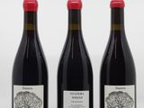 three bottles of red wine are lined up on a white surface