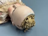 a doll head with a gold leaf sticking out of it ' s mouth