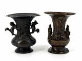 two bronze vases sitting side by side on a white surface